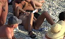 Seorang wanita berambut coklat telanjang dengan vagina berbulu bersantai di pantai