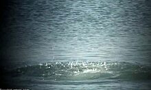 Loira deslumbrante com peitos grandes desfrutando de um mergulho magro em uma praia de nudismo
